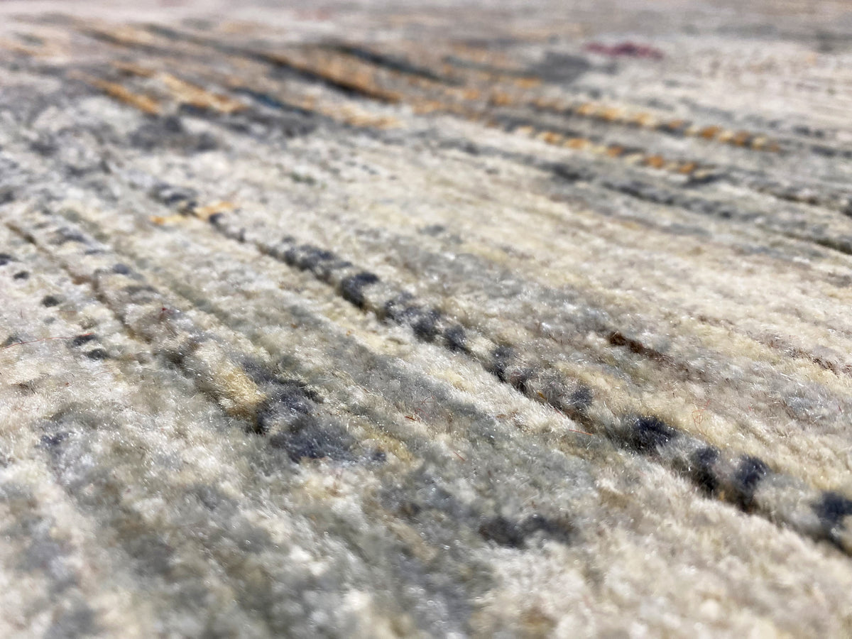 Gabbeh-Luri Teppich Close-up: hellgraue Struktur mit dunklen und goldenen Streifen