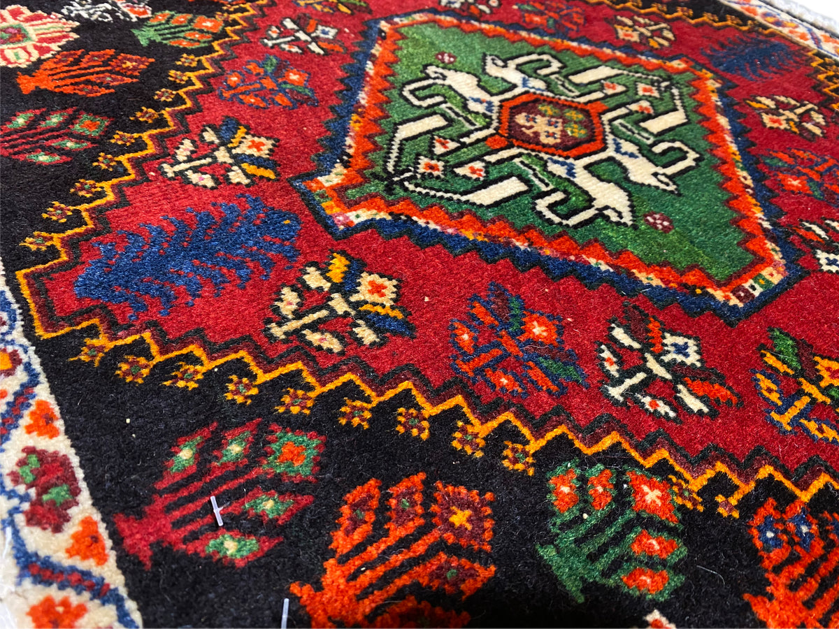 Poshti-tapijt, detailweergave van een hoek: meerkleurige geometrische ornamenten op een zwarte ondergrond