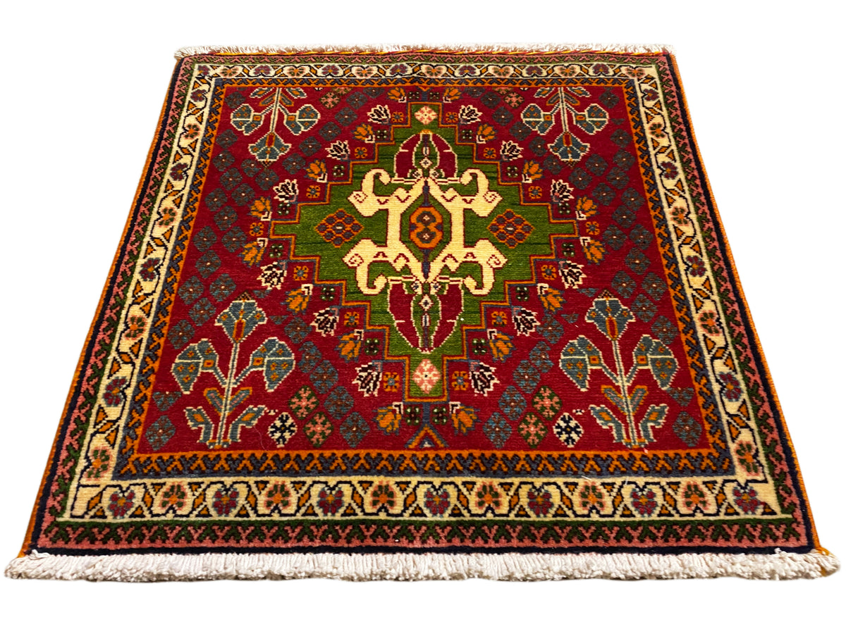 Oosters tapijt met rood middenmotief, groene details en beige rand, met franjes
