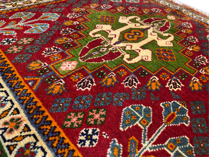 Close-up van het oosterse tapijt: rood veld met bloemmotieven, groene accenten