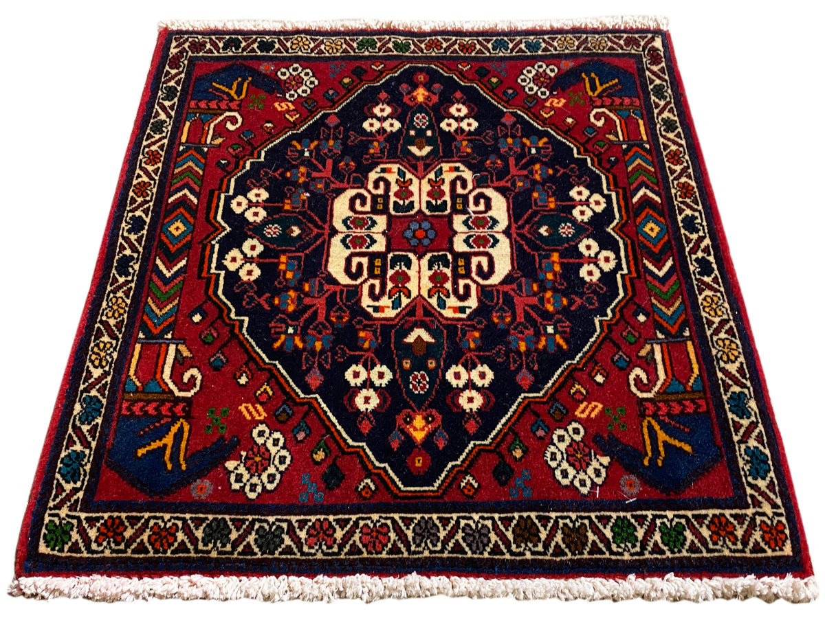 Vierkant tapijt met centraal medaillon, rood-blauwe ornamenten en korte franjes