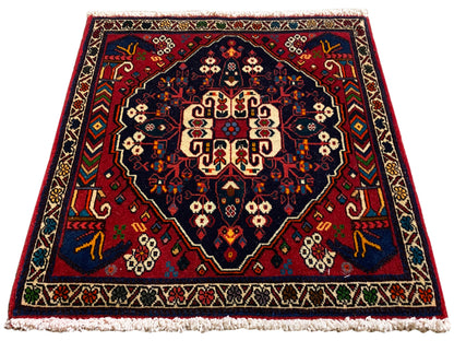Vierkant tapijt met centraal medaillon, rood-blauwe ornamenten en korte franjes