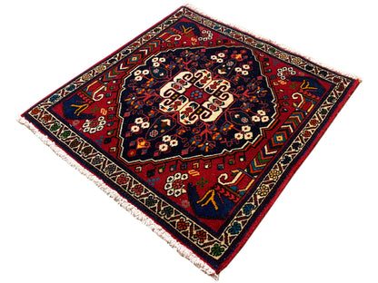 Vierkant vloerkleed met decoratieve rand, rood-blauw patroon en crèmekleurig middenvlak