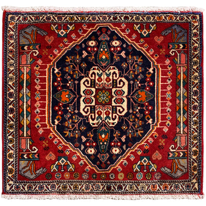 Vierkant tapijt met rode achtergrond en donkerblauw centraal motief, met franjes