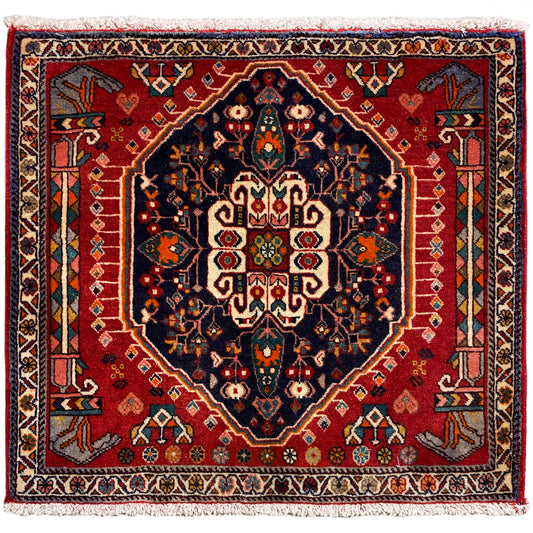 Vierkant tapijt met rode achtergrond en donkerblauw centraal motief, met franjes