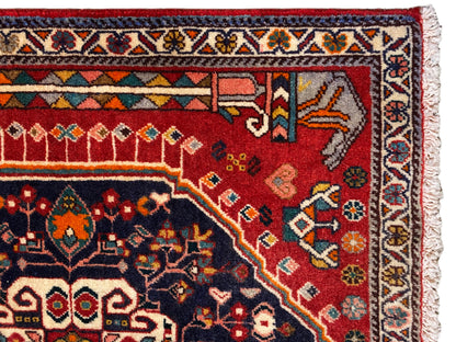 Tapijndetail: rood en blauw ornamentvlak met veelkleurige rand en franjes