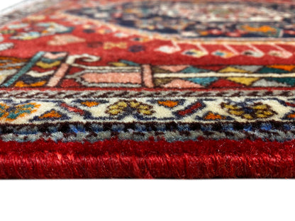 Tapijtrand in detail: rode pool, veelkleurige patroonrand en rafelige franjes