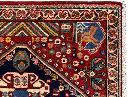 Tapijtdetail: rood veld met geometrische motieven, blauw hoekmotief en boortrand