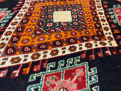 Detailweergave van een Poshti-tapijt met een oranjegele centrale ruit, kleine ornamentelementen en een wit middenstuk