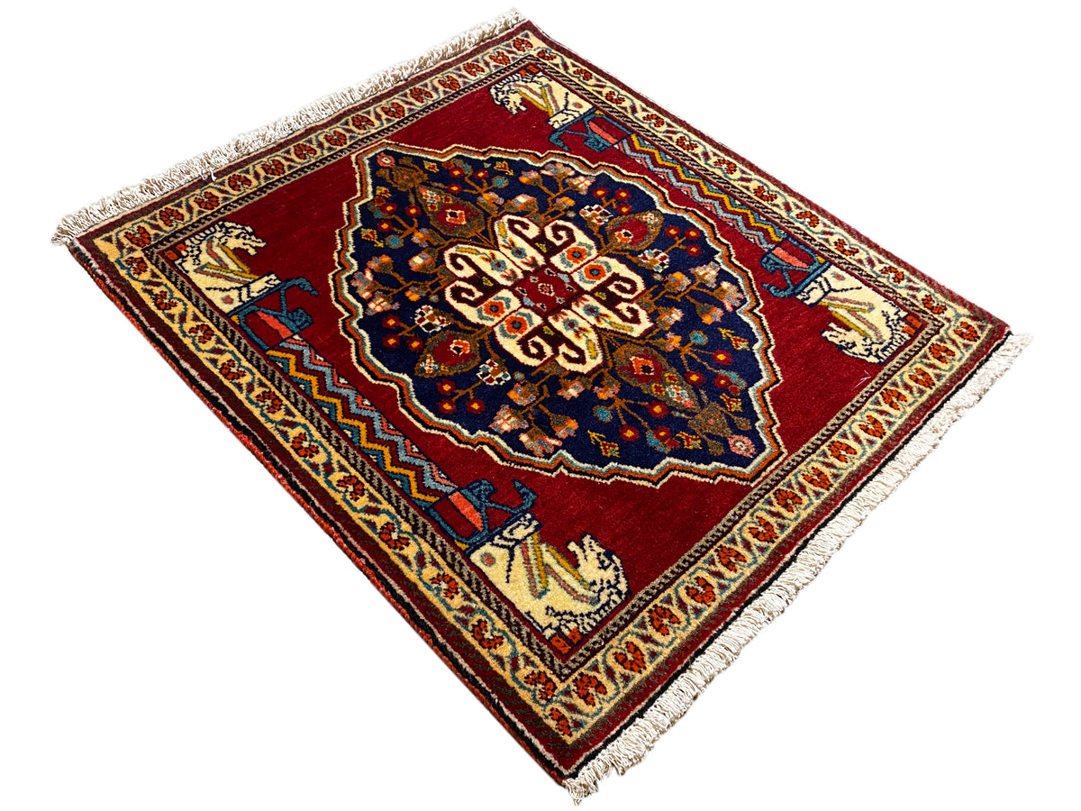 Tapijt in ruitpatroon met rode achtergrond, donkerblauw midden en franjes