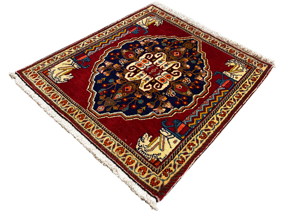Tapijt met rode basis, donkerblauw centraal motief, beige sierstroken en franjes