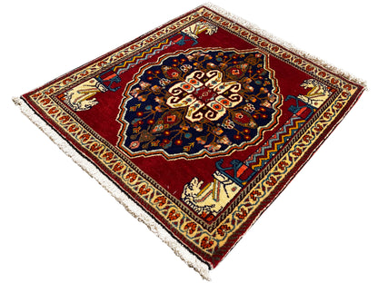 Tapijt met rode basis, donkerblauw centraal motief, beige sierstroken en franjes