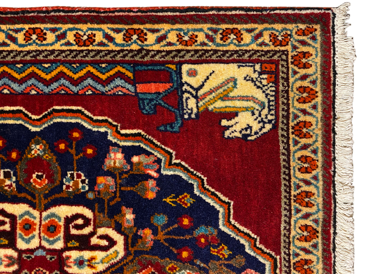 Detailweergave: rood en donkerblauw tapijtpatroon met beige dier-/figuurelementen