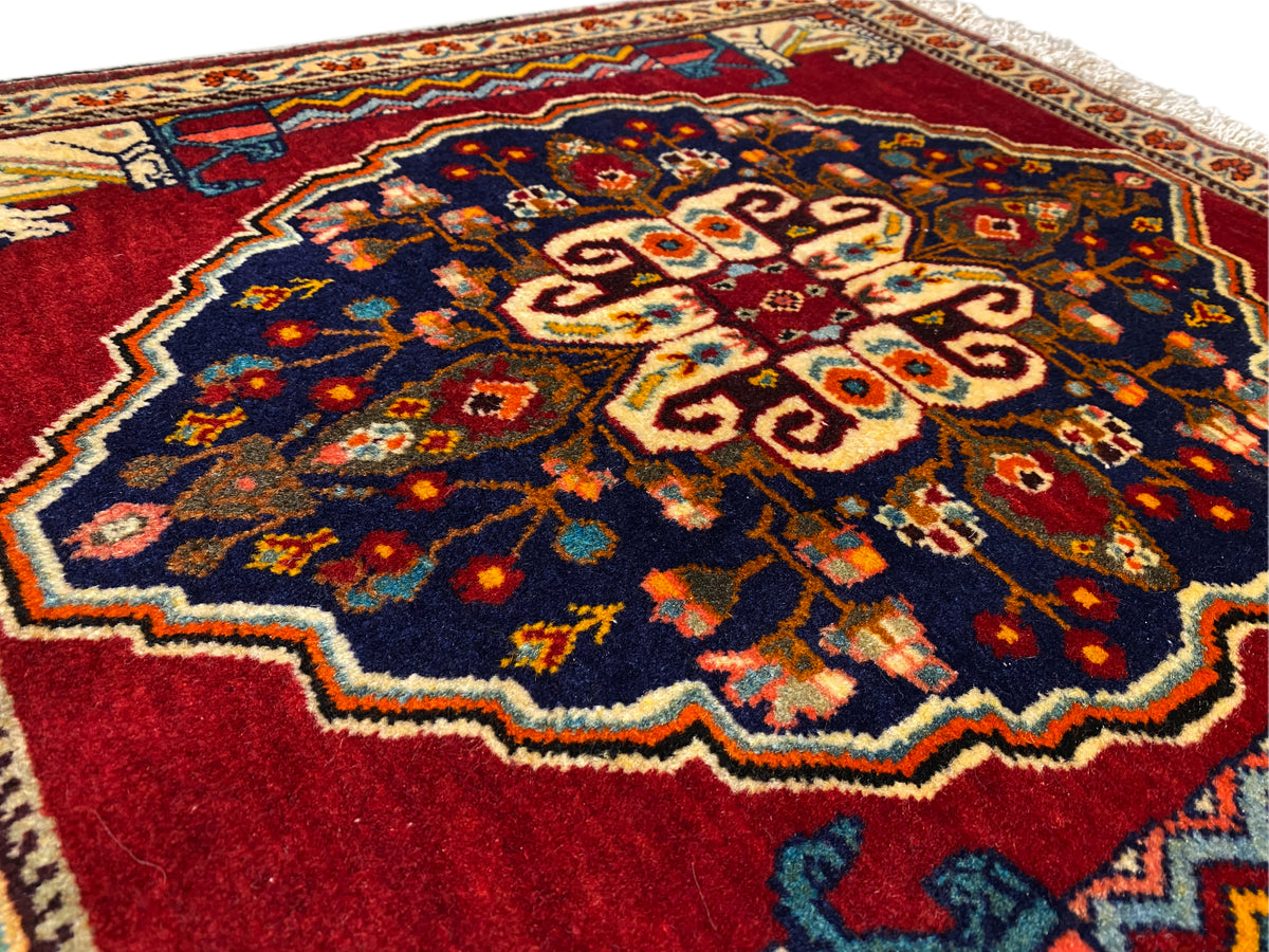 Close-up van het midden van het tapijt: donkerblauw, rood, beige en veelkleurige ornamentvlakken