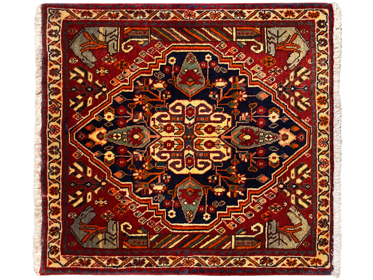 Tapijt 65x59 cm met een rode basis, blauwgrijze ornamenten en een symmetrisch patroon