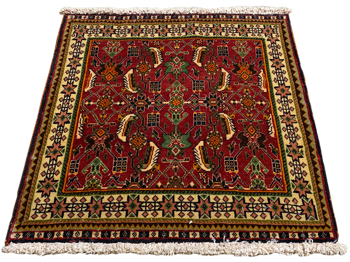 Poshti-vloerkleed 63x61 cm, schuin aanzicht: rood ornamentpatroon in groen en beige.
