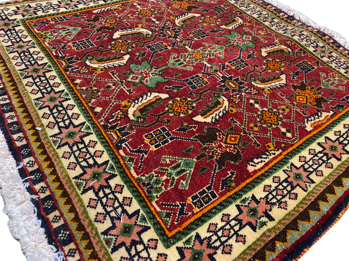 Poshti-tapijt 63x61 cm Detailaanzicht: rood patroon met dieren-/ornamentmotieven en sierrand.