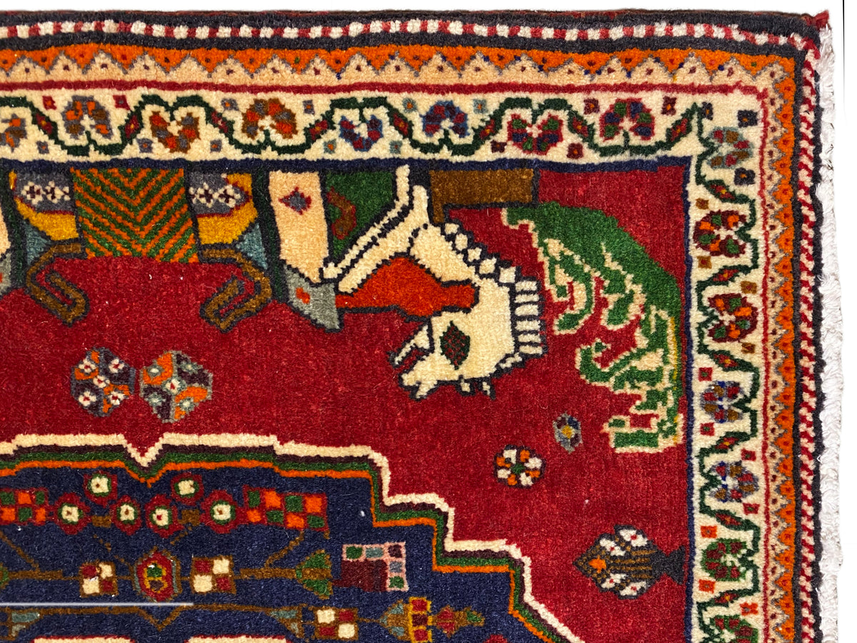 Close-up van een Poshti-tapijt, rood veld met dieren, blauwe sierboord en patroonrand