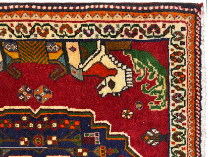 Close-up van een Poshti-tapijt, rood veld met dieren, blauwe sierboord en patroonrand