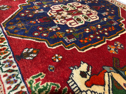 Close-up van Poshti-tapijt, rood veld met blauwe ornamentkrans en diermotieven