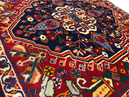 Close-up van tapijt: blauw patroon met rode en gele ornamenten, geweven structuur