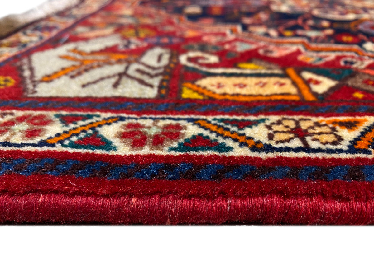 Tapijndetail aan de zoom: rood-blauwe rand, veelkleurige patronen en korte franjes
