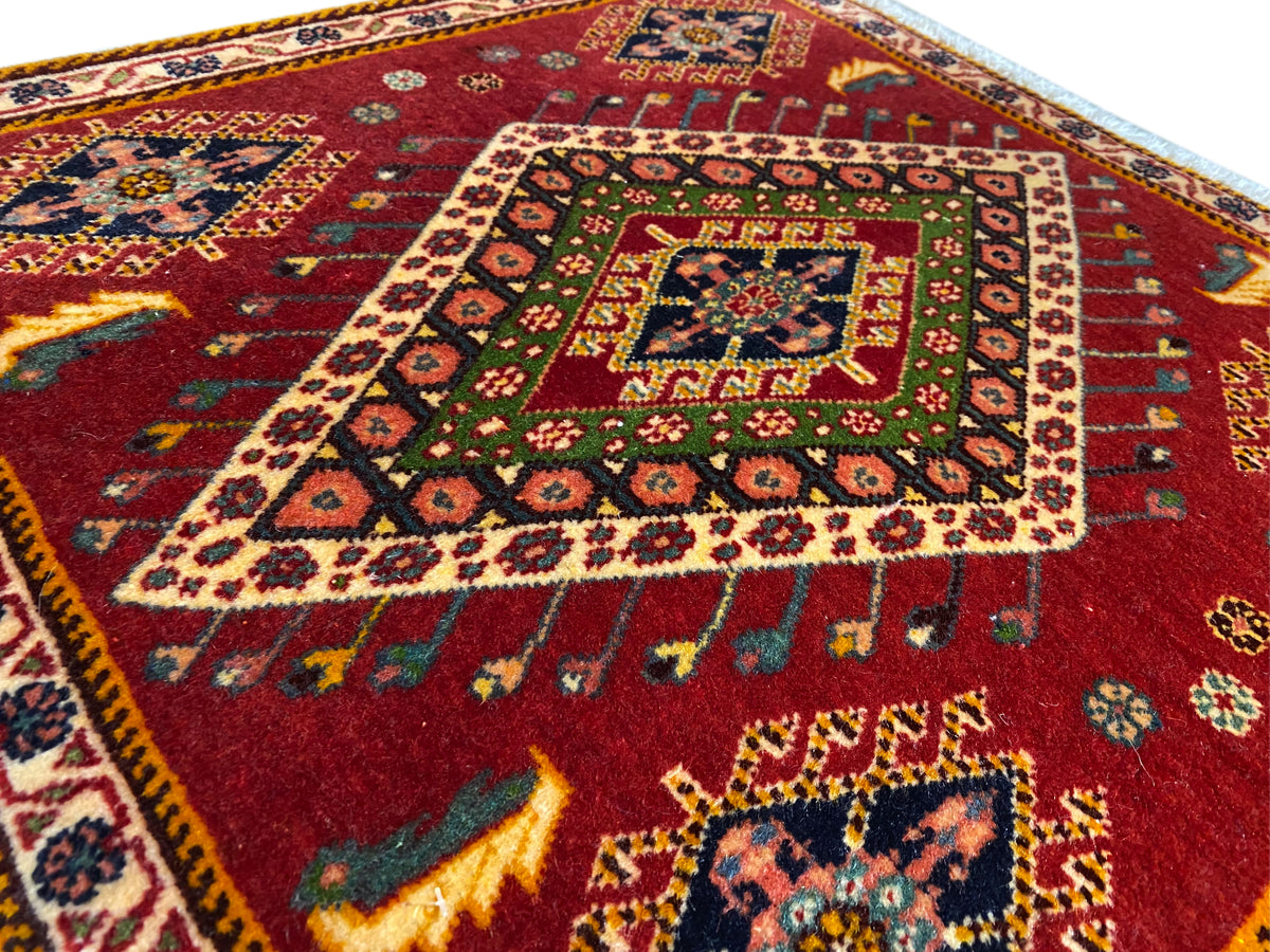 Detail van een Poshti-tapijt: rood patroon met kleurrijk medaillon en omlopende rand