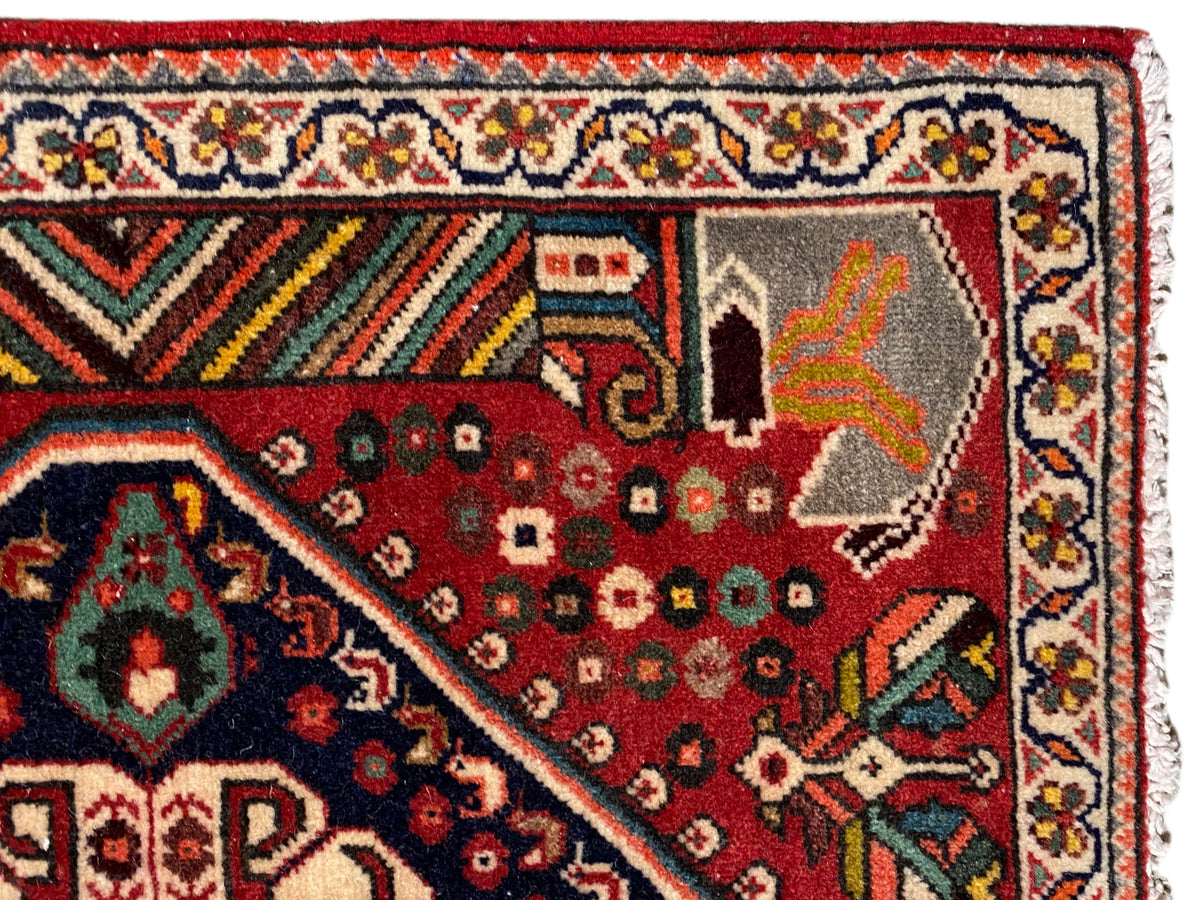 Detailweergave: rood tapijt met ornamentele motieven, veelkleurige rand en franjes