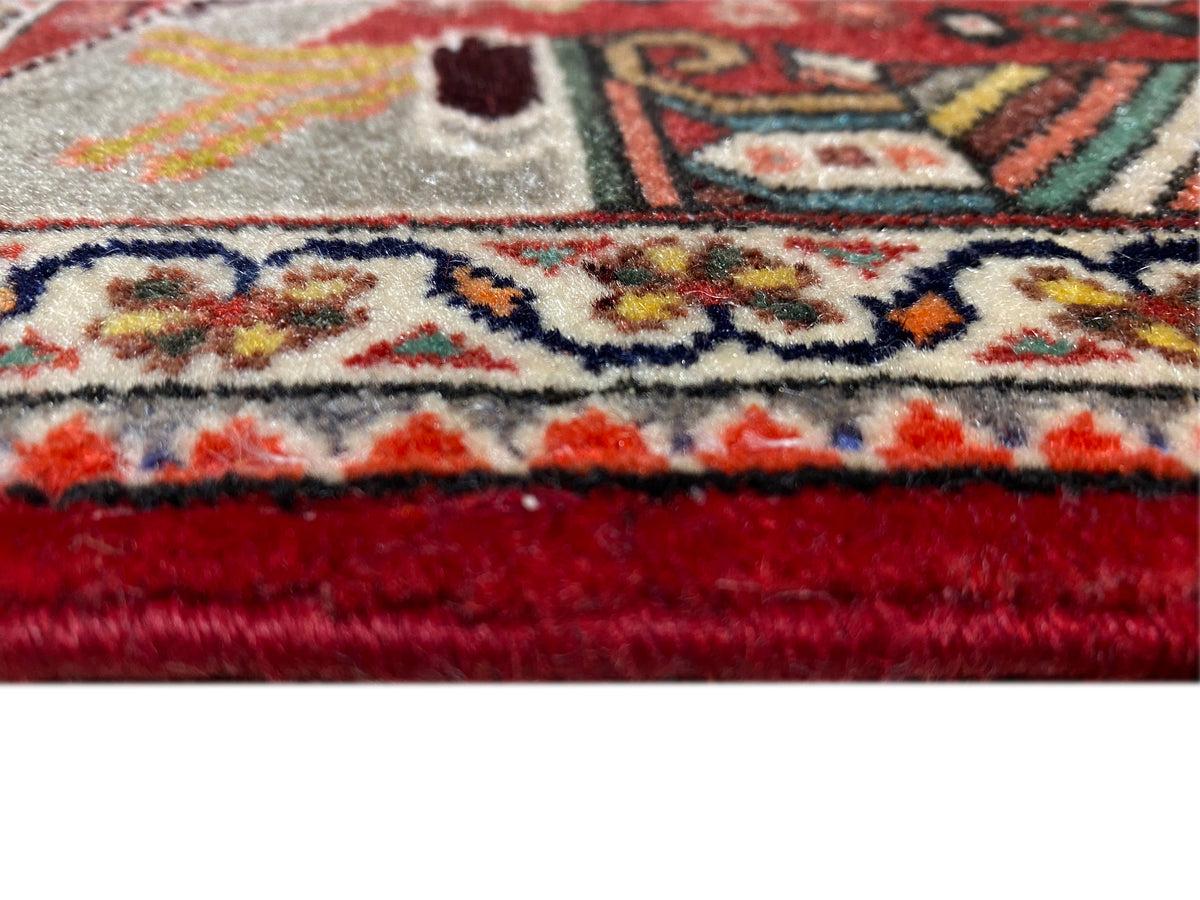 Close-up: rug edge with fringes, red finish and dense ornamental pattern