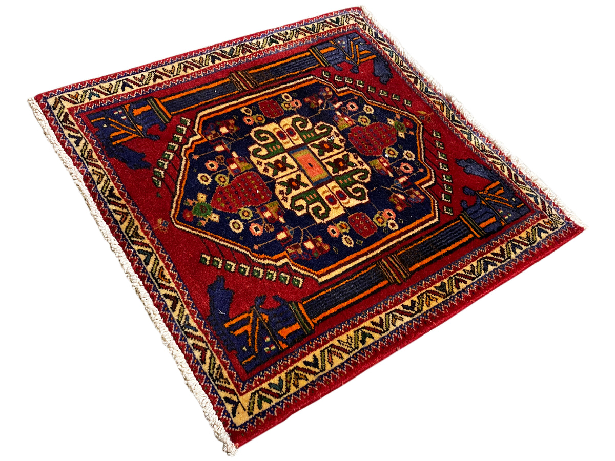 Poshti-tapijt 66x62 cm diagonaal: blauw-rode rand met talrijke ornamenten.