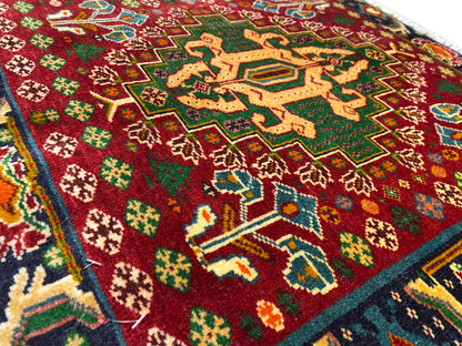 Detail van de voorkant van een tapijt met een rood vlak, stervormige patronen en turquoise lijnen, gestructureerde pool