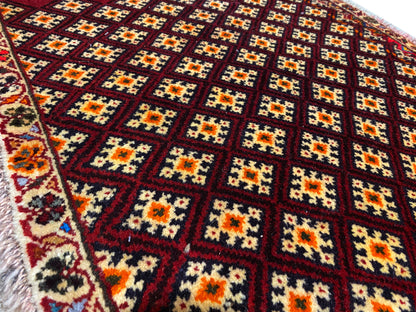 Poshti-tapijt 61x59 cm: close-up van het patroon met kleurrijke ruiten op een donkerrode ondergrond