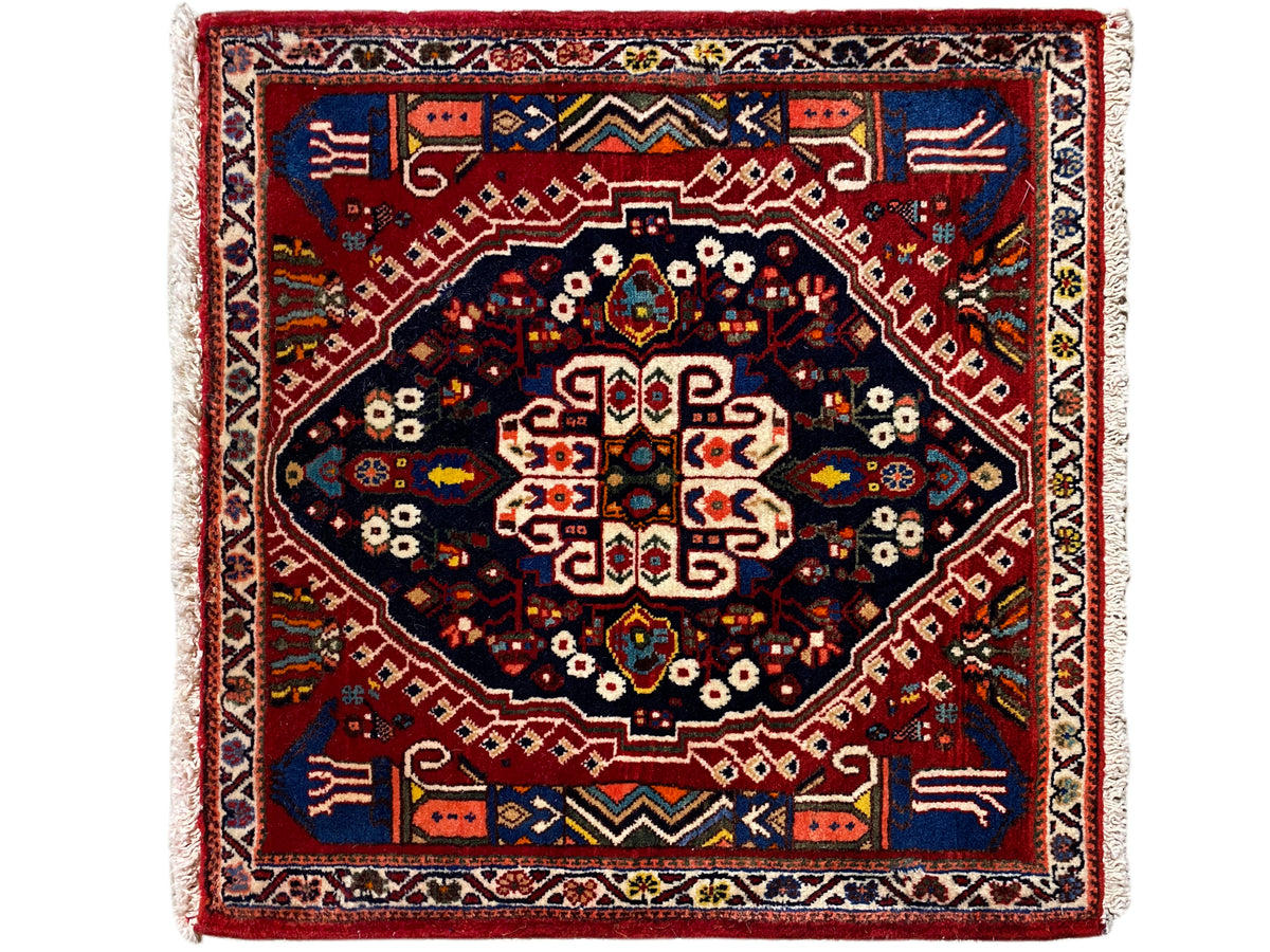 Rechthoekig tapijt met rode rand, donkerblauw middenvlak en geometrisch patroon
