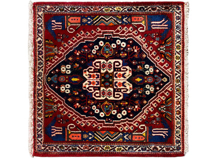 Rechthoekig tapijt met rode rand, donkerblauw middenvlak en geometrisch patroon