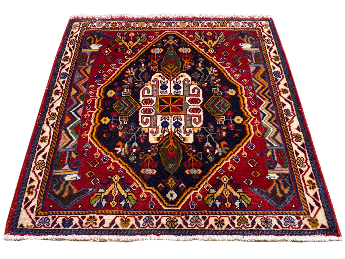 Poshti-tapijt (67×67 cm) in schuin aanzicht: rand, rood midden, donkerblauw