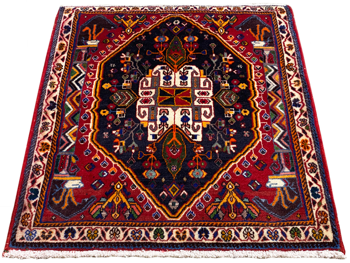 Tapijt 70x67 cm met donkerblauwe basis, rode rand en symmetrisch medaillonpatroon
