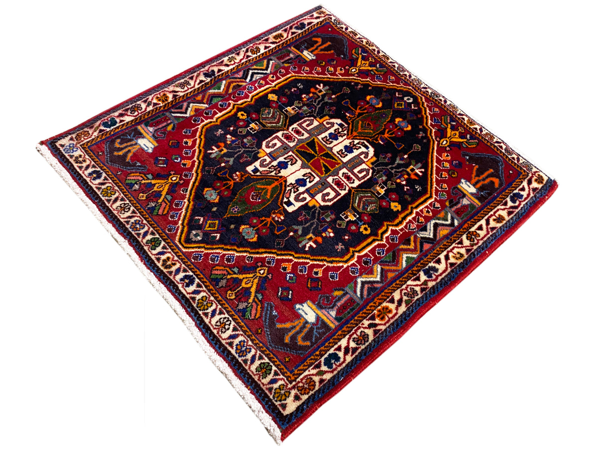 Tapijt 70x67 cm: donker ornamentpatroon in het midden, rood-blauw kleurenpalet, randborduurwerk