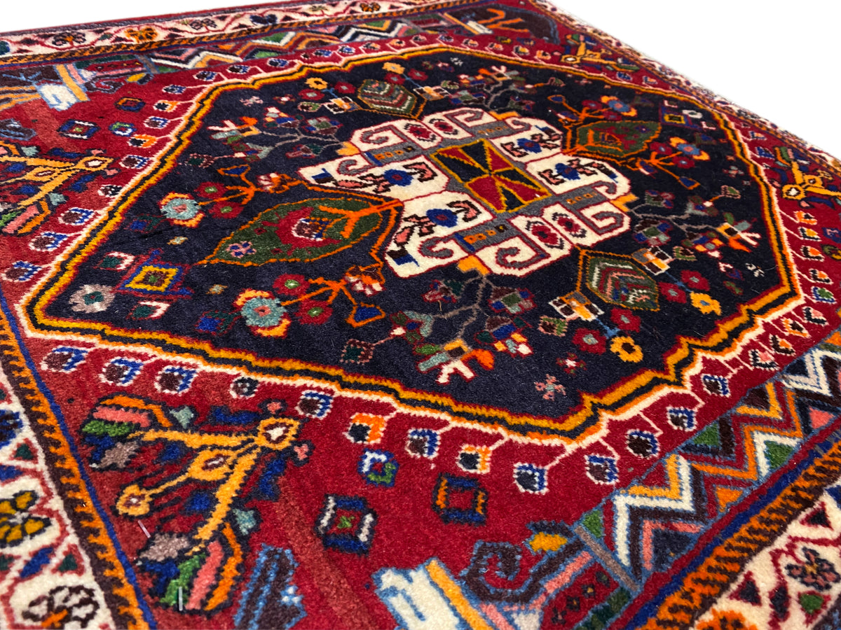 Close-up van het tapijtoppervlak met geometrisch ornament in blauw, rood en goud