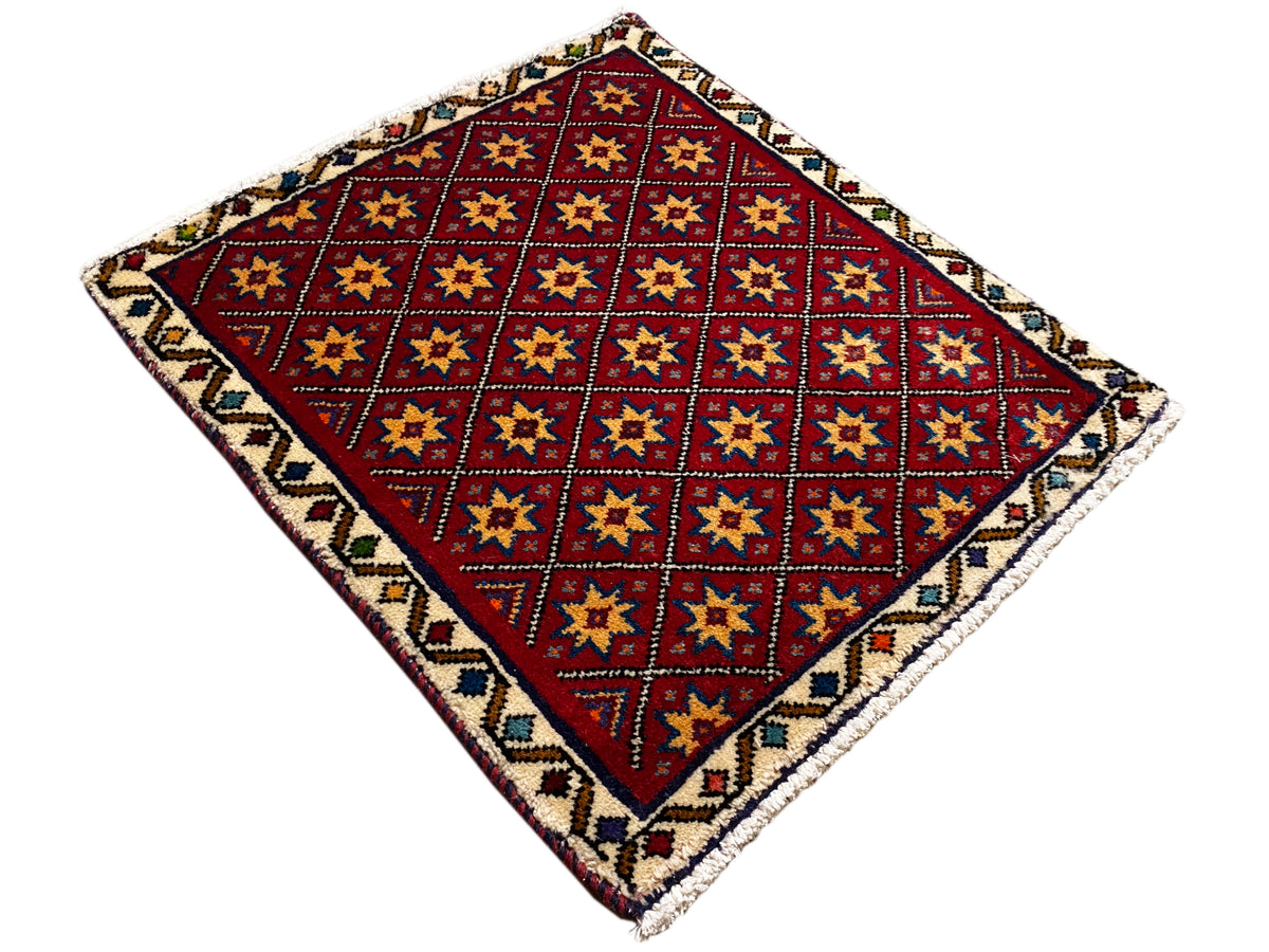 Vierkant tapijt uitgespreid met een rood geometrisch patroon en een kleurrijke rand