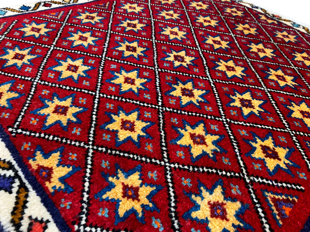 Close-up van het tapijt: rood ruitpatroon met gele en blauwe sterren