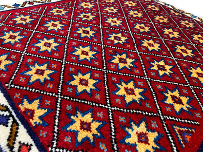 Close-up van het tapijt: rood ruitpatroon met gele en blauwe sterren