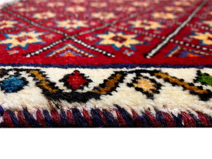 Tapijndetail: rood-blauw patroon met franjes aan de onderrand